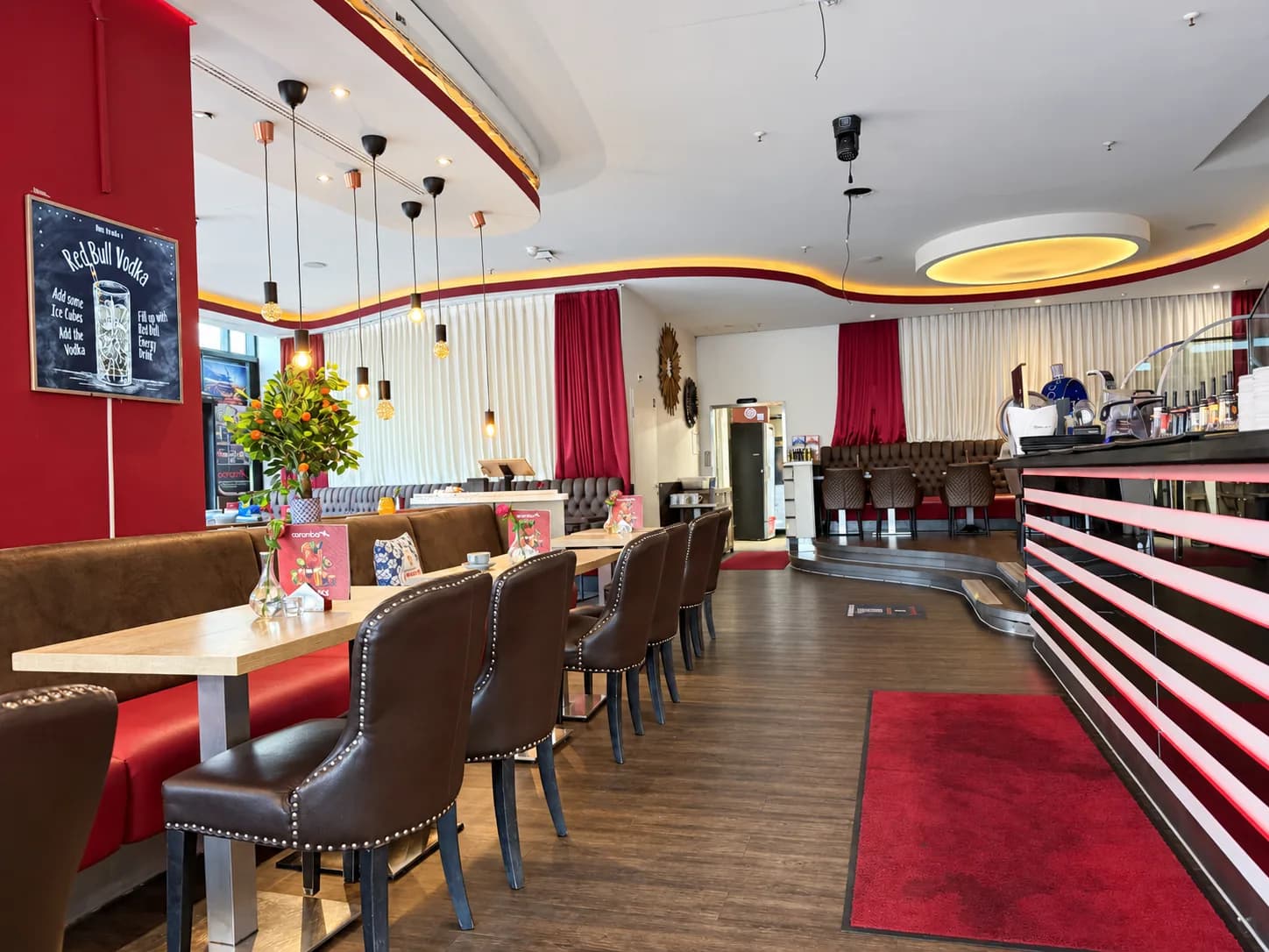 Carambar bar counter with bench seating, pendant lights and red curtains during the day