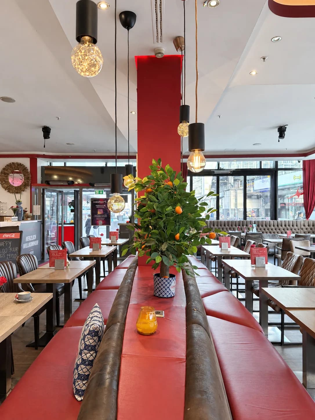 Long red bench with a small orange tree in the Carambar restaurant