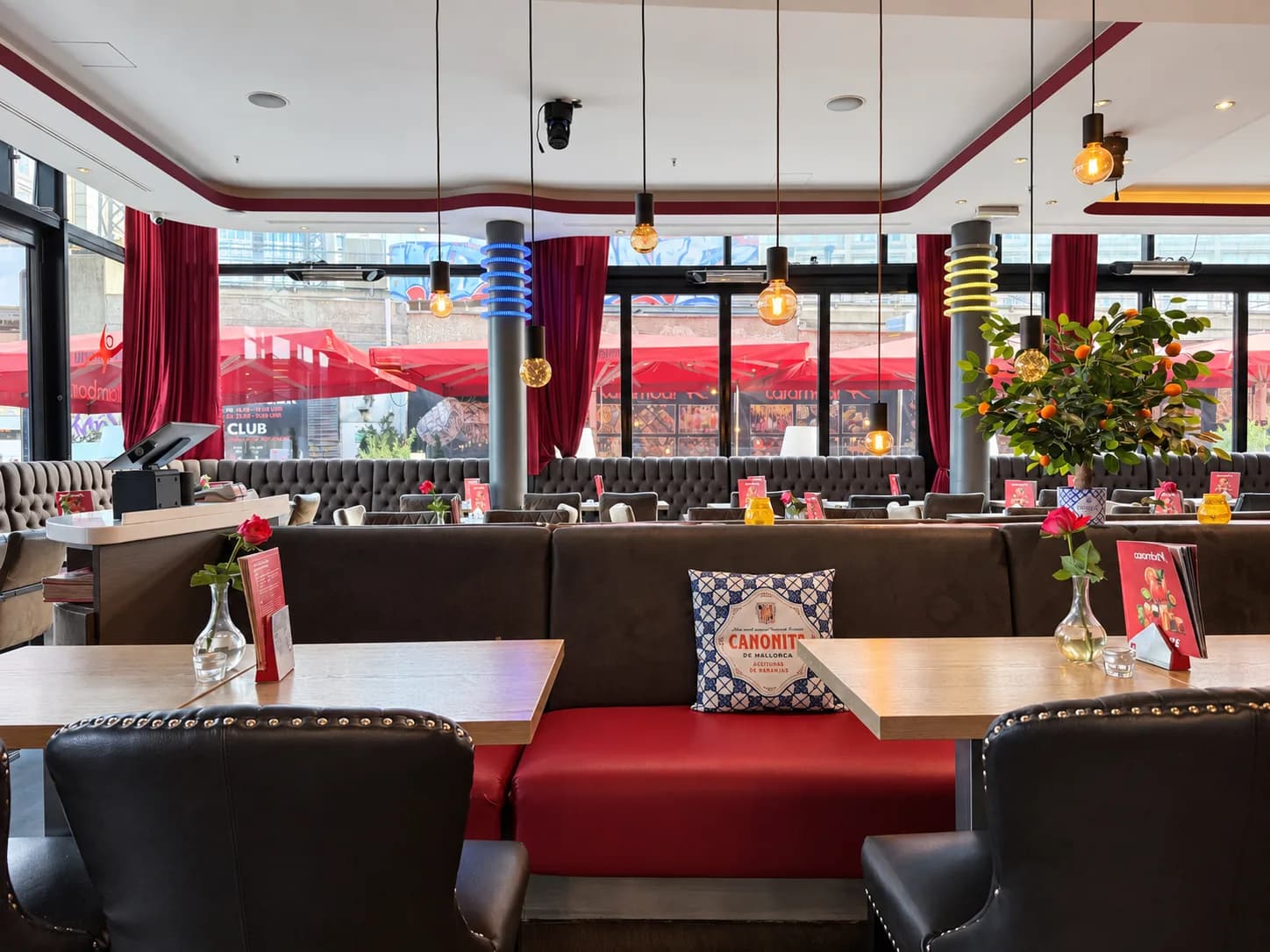Booths with red upholstery in the Carambar restaurant, with the window front behind