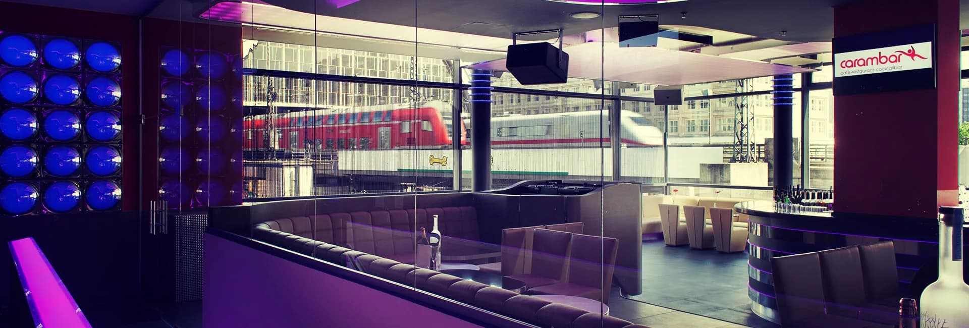 Carambar club with a blue lit wall of spheres, lounge seating, bar and a view of the trains at Alexanderplatz