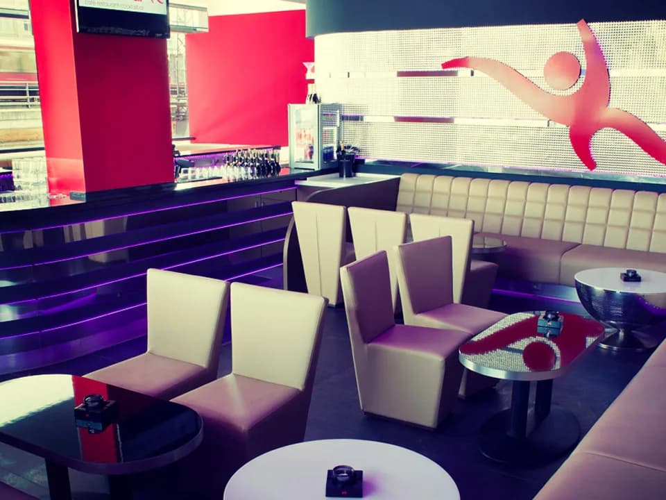 Armchairs and bench seating in the Carambar club lounge, with the red Carambar figure on the wall