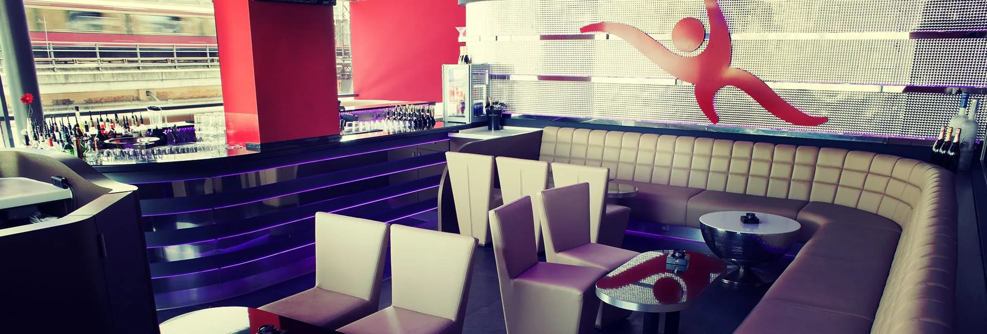 Carambar club lounge with bar, armchairs, curved bench seating and the red Carambar figure on the illuminated wall